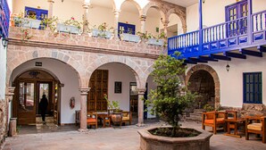 A courtyard with stone arches, wooden furniture, and potted plants. - Estancia San Pedro Hotel (Cusco)