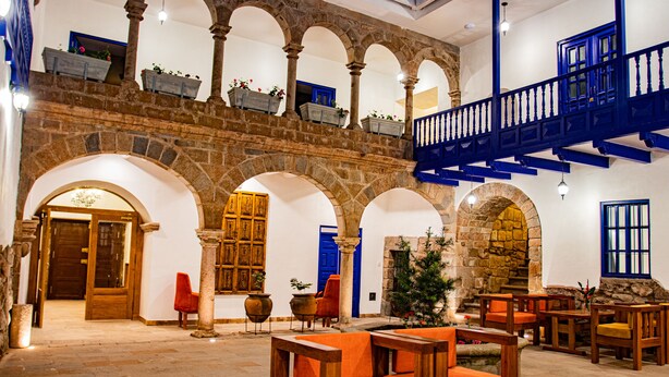 A spacious lobby with a high ceiling, stone arches, and a blue staircase. - Estancia San Pedro Hotel (Cusco)