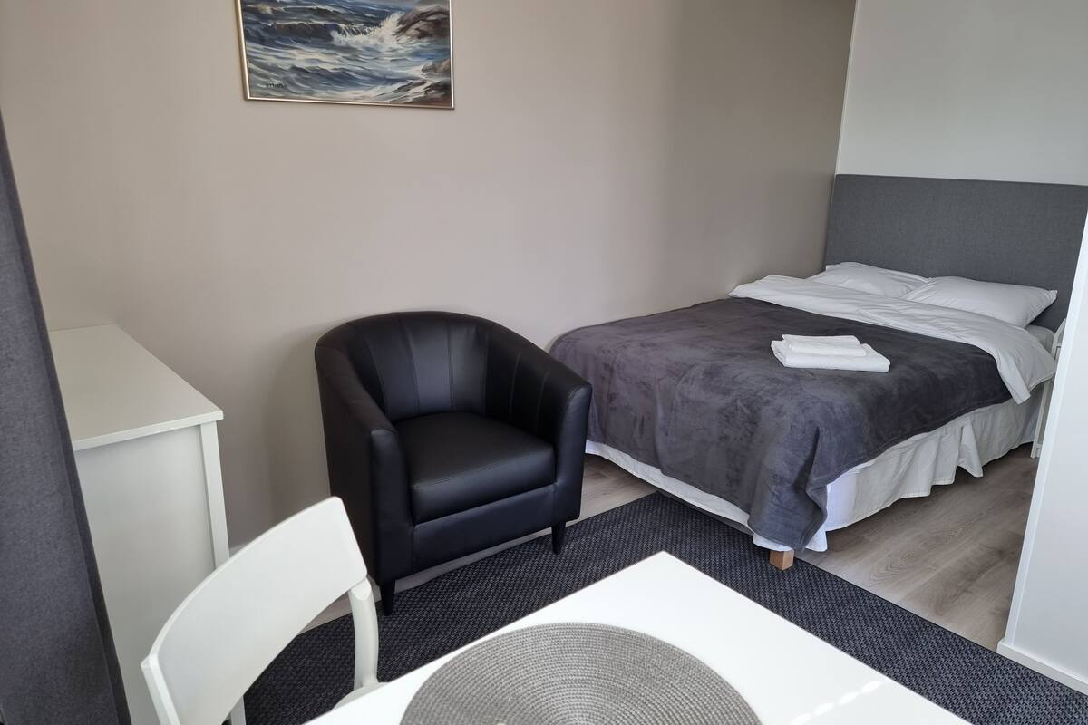 Une petite chambre à coucher, bien rangée, avec un lit, une chaise, un bureau et un tableau accroché au mur.