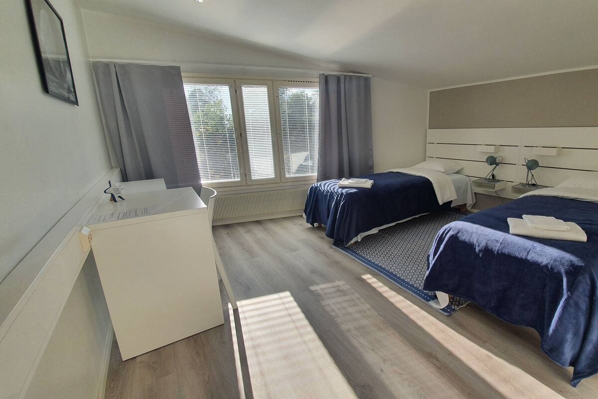 Une chambre d’hôtel avec deux lits, un bureau et une fenêtre avec des rideaux.