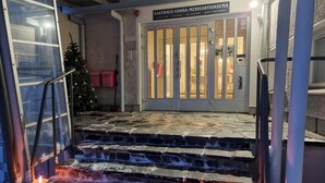 L’entrée d’un hôtel, avec un escalier en pierre menant à une porte dotée de panneaux de verre et d’une enseigne au-dessus.