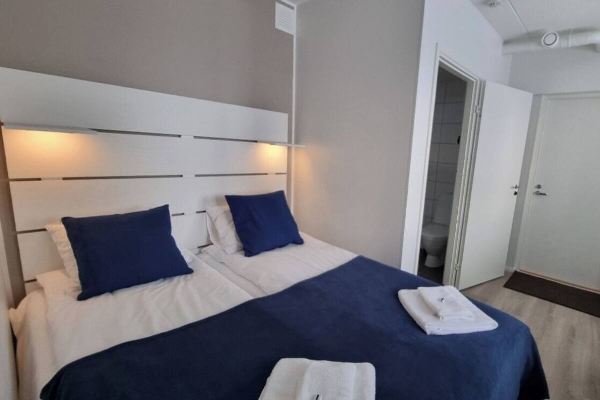 Une chambre d’hôtel avec un grand lit, deux oreillers, un bureau et une chaise.