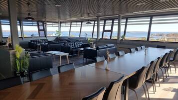 Enjoy meals in this stylish dining area with a long table, black chairs, and a geometric ceiling.