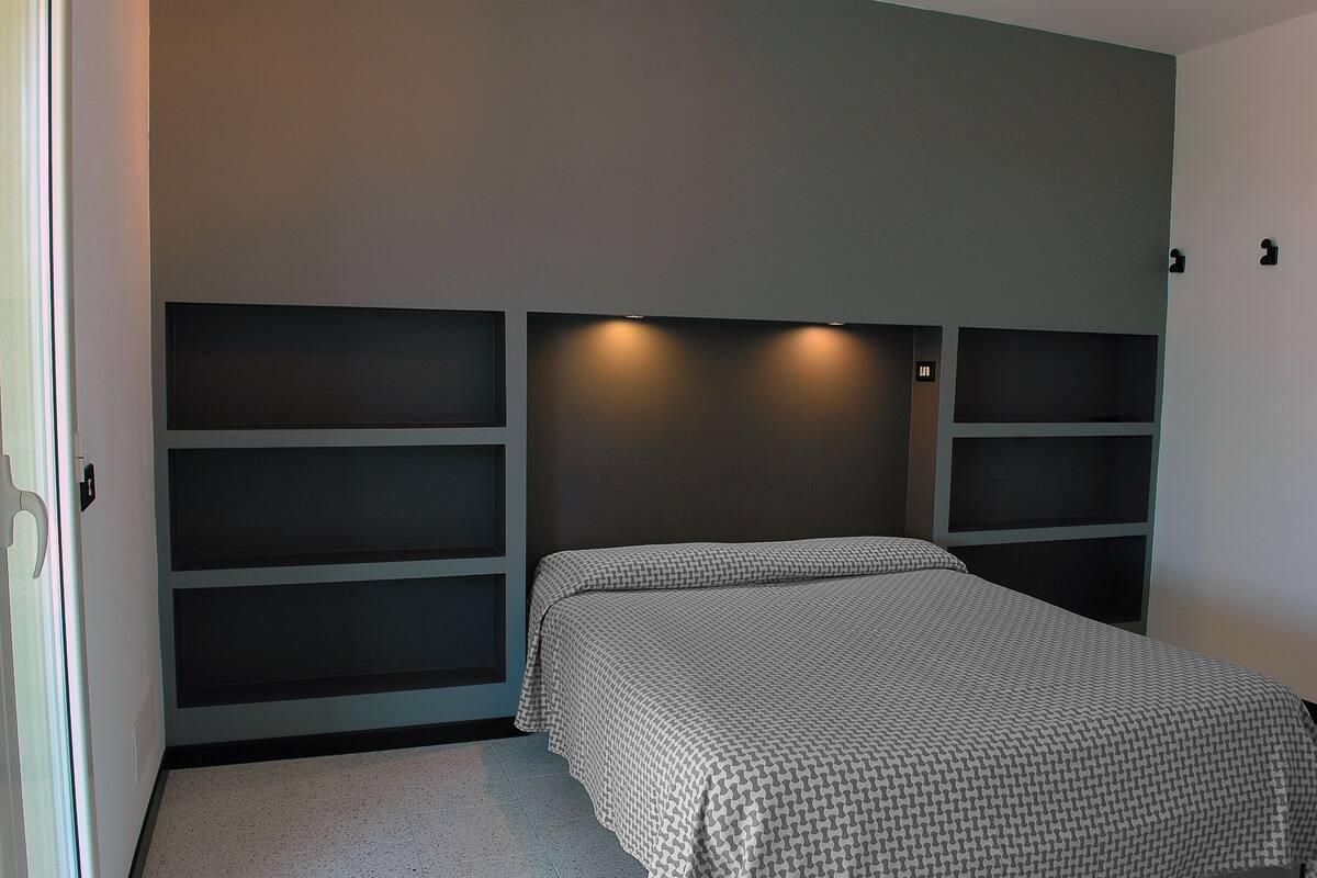 A bedroom with a bed, built-in shelving, and recessed lighting.