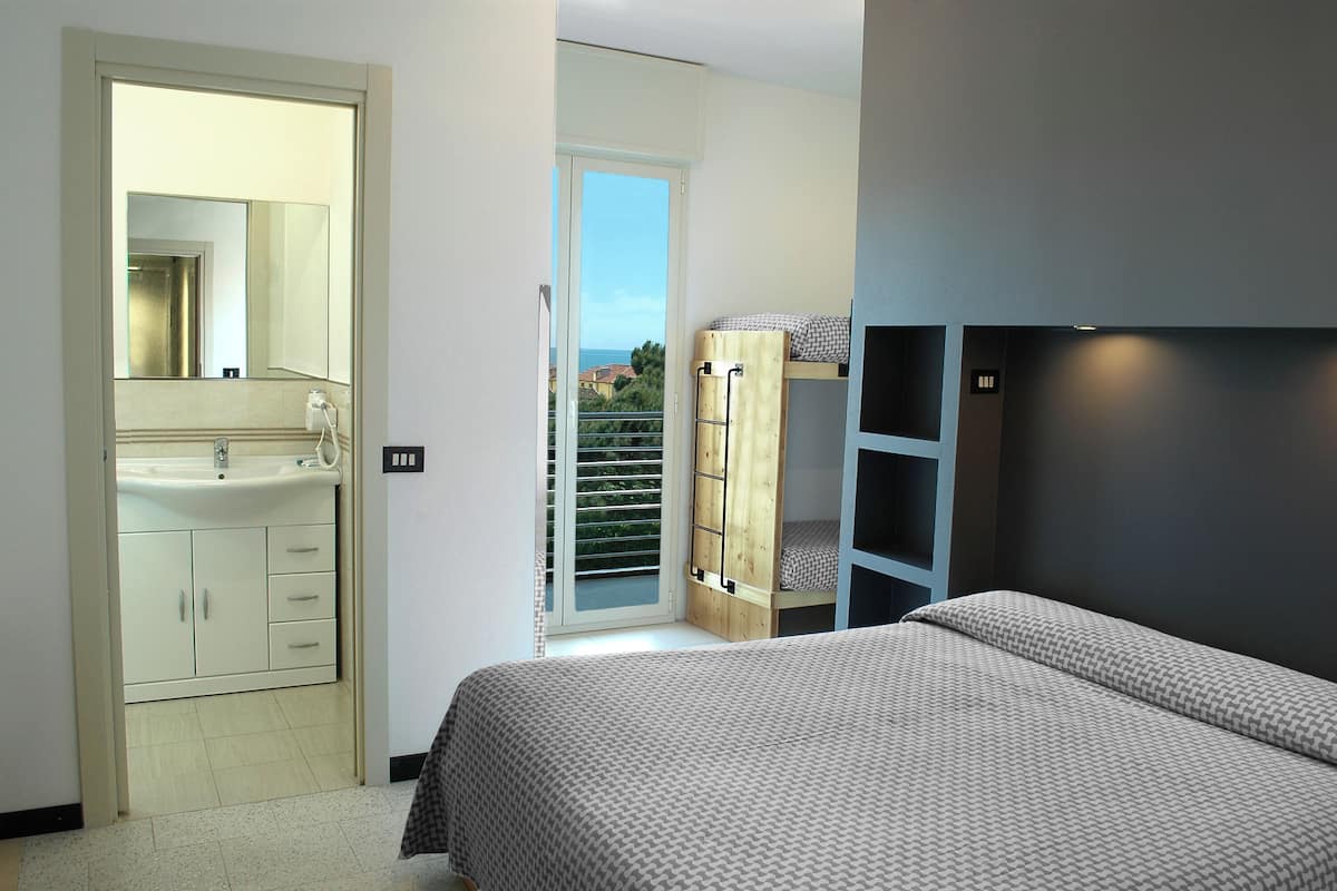 A bedroom with a bed, a wardrobe, a bathroom with a sink, and a balcony with a view.
