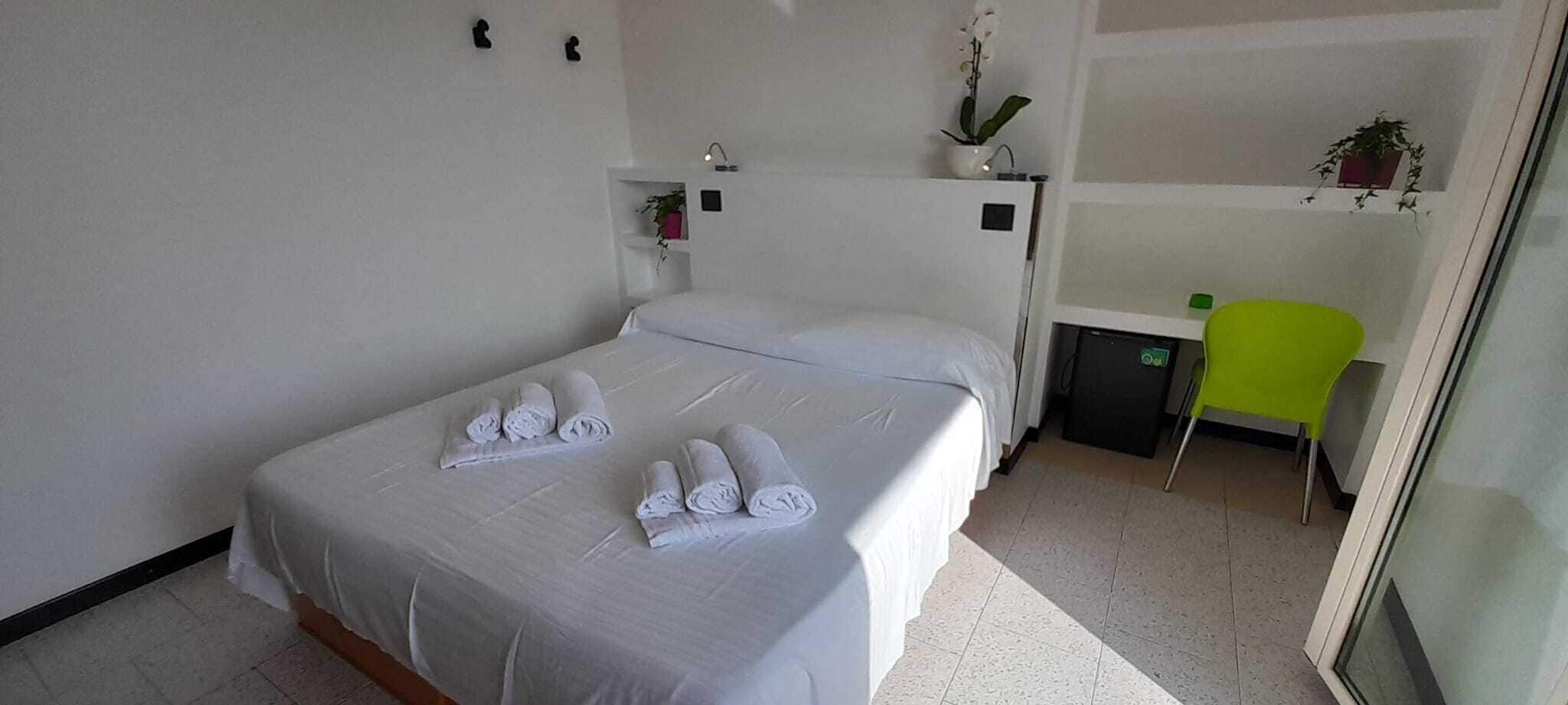 Ein Hotelzimmer mit zwei Betten, einem Schreibtisch, einem Stuhl und einem kleinen Kühlschrank.