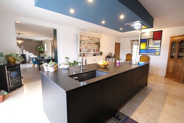 A modern kitchen with a central island, built-in appliances, and a dining area with chairs and a table.