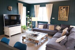 A living room with a television, sofa, coffee table, and decorative plants.