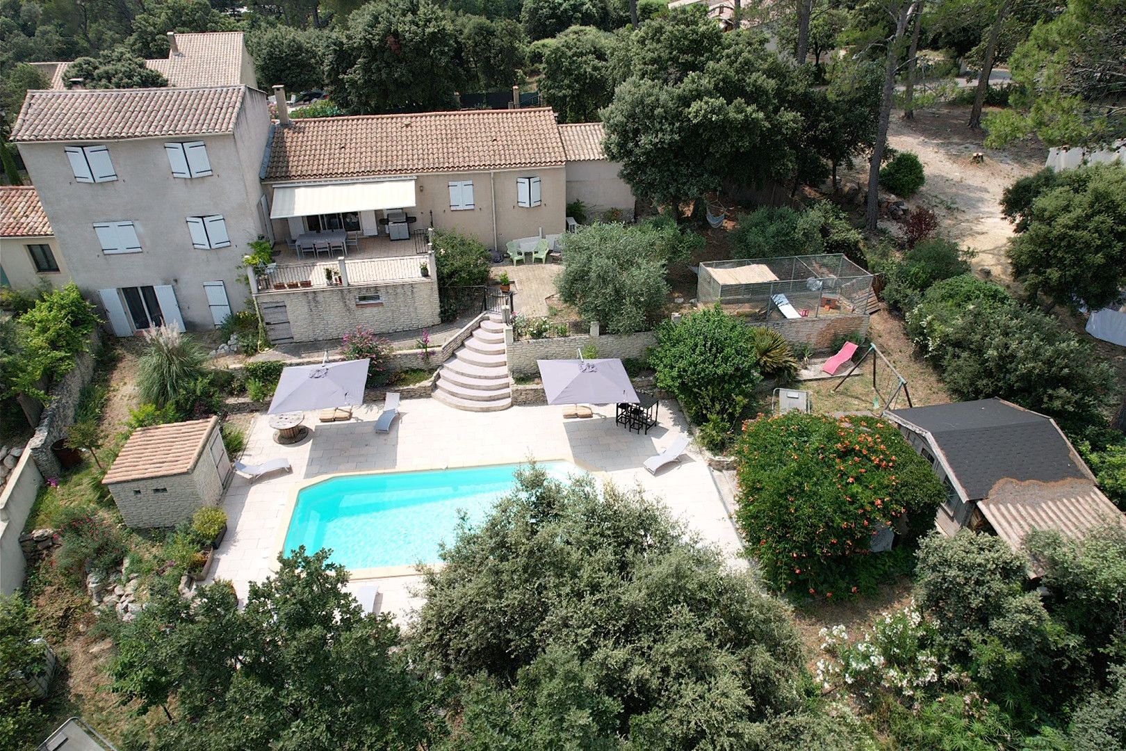 A residential property with a swimming pool, outdoor seating, and a garden.