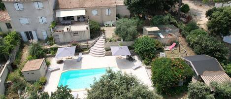 A residential property with a swimming pool, outdoor seating, and a garden.