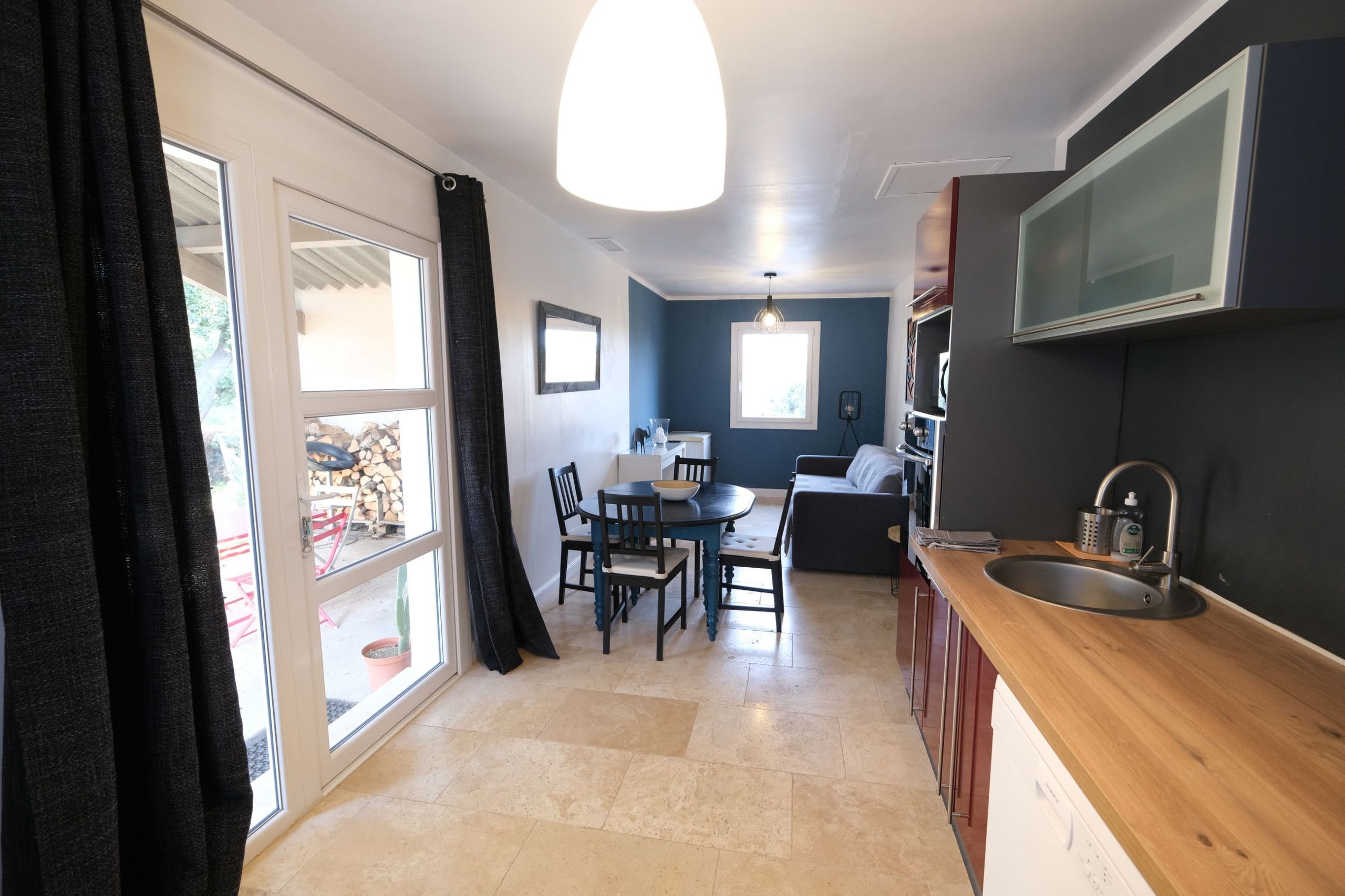 A compact kitchen with a dining area, a large window, and a built-in TV.