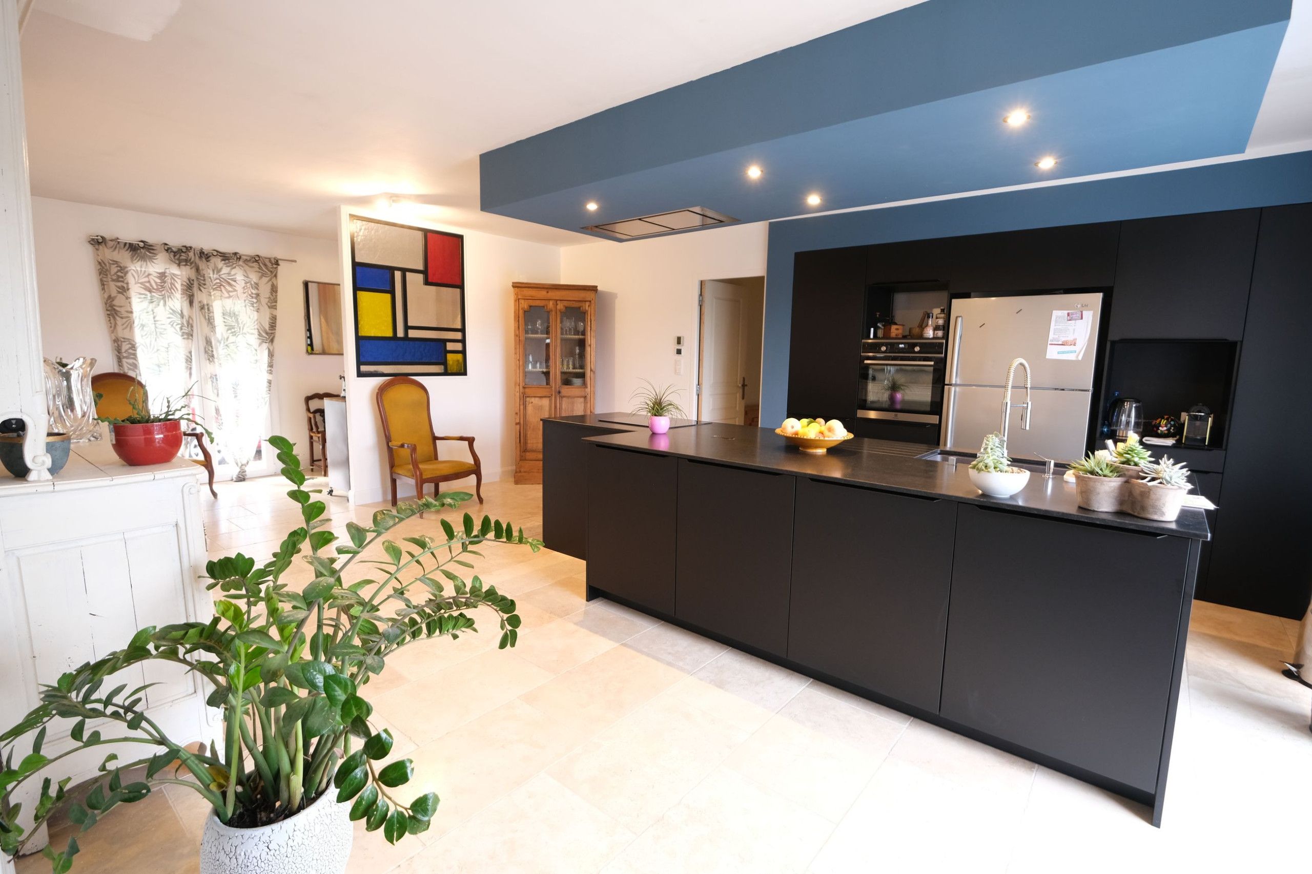 A modern kitchen with a central island, built-in appliances, and a large window.