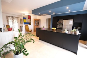 A modern kitchen with a central island, built-in appliances, and a large window.