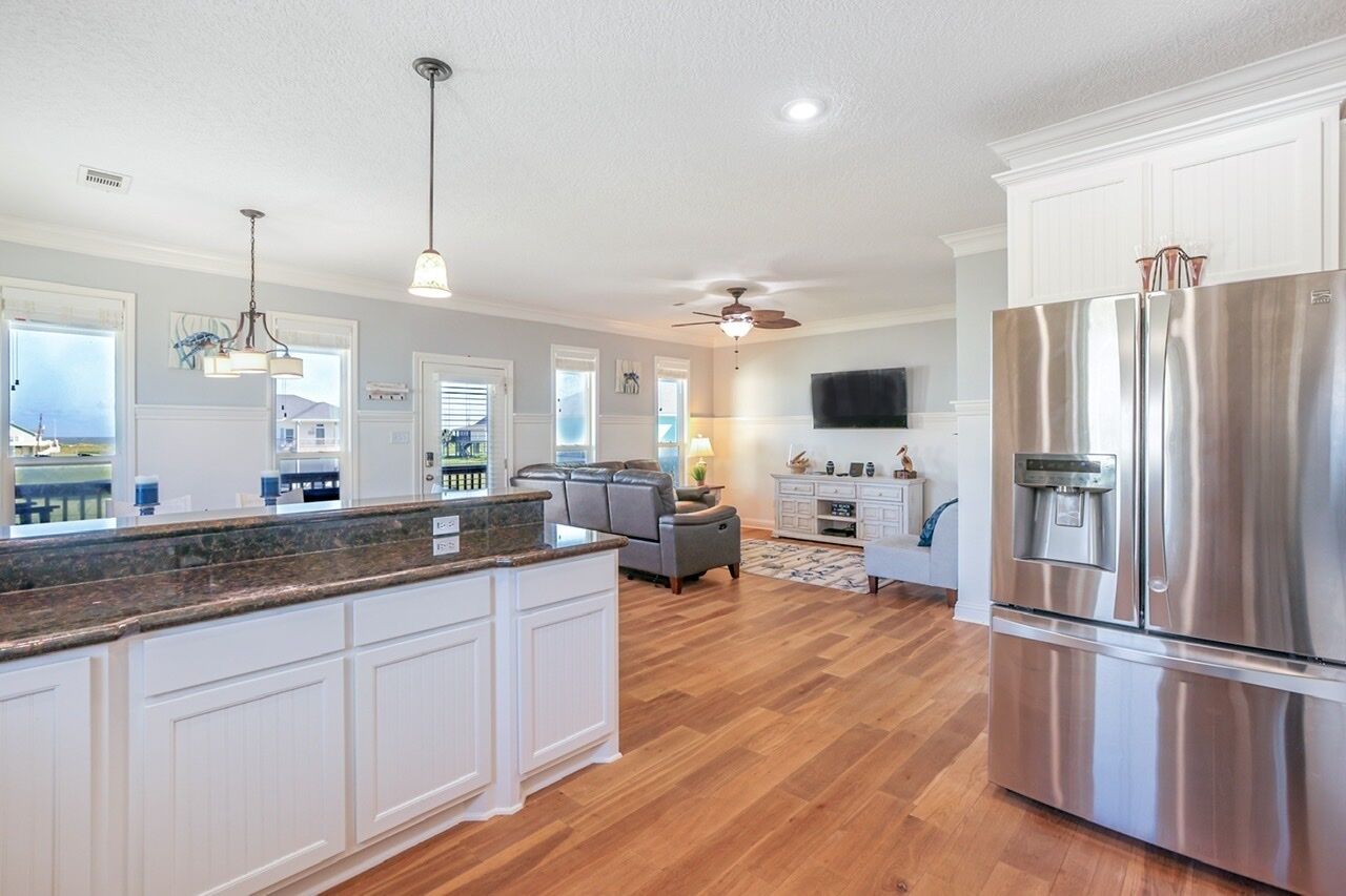 A spacious kitchen with a large island, stainless steel appliances, and a ceiling fan.