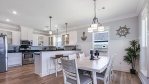 Una cocina moderna con armarios blancos, una isla central e iluminación colgante.