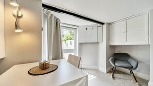 A modern, well-lit room with a white table, a grey chair, and a ceiling-mounted light fixture. - Lovely Apartment - Central Oxford - Pass the Keys (Oxford)