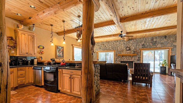 A spacious kitchen with wooden cabinets, a stone wall, and a fireplace. - Riverfront | Close to Skiing, New Hot Tub! (Pagosa Springs)