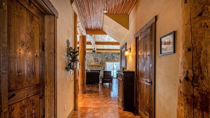 A wooden hallway with a stone fireplace, wooden doors, and a tiled floor. - Riverfront | Close to Skiing, New Hot Tub! (Pagosa Springs)