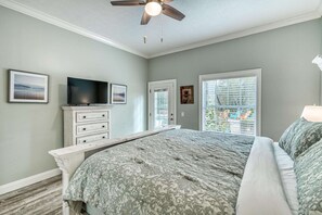 Un dormitorio con una cama, un aparador, un televisor y una ventana con persianas.