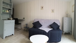 Una sala acogedora con un sofá, una mesita redonda, un aparador y una silla.