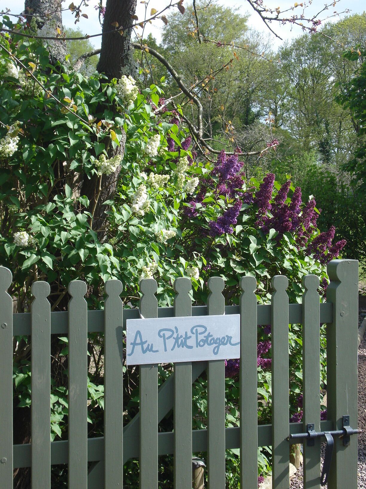 A wooden fence with a sign that reads "Au Petit Potager".