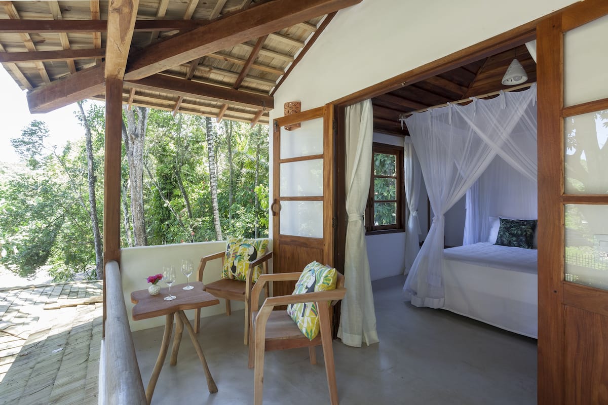 Una habitación con cama, una mesa con sillas y vistas al bosque.