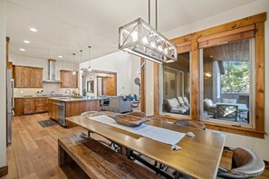 A spacious kitchen with wooden cabinets, a large dining table, and a view of the outdoor patio.