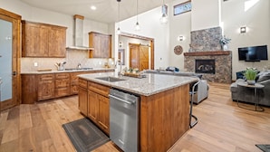 A spacious kitchen with wooden cabinets, granite countertops, and a central island. - Family Getaway with Access to Forest House (Sunriver)