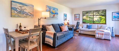 A living room with a dining area, two sofas, a coffee table, and artwork on the walls.