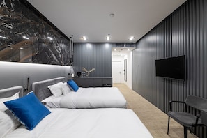 Una habitación de hotel moderna con dos camas, televisión y zona de estar.