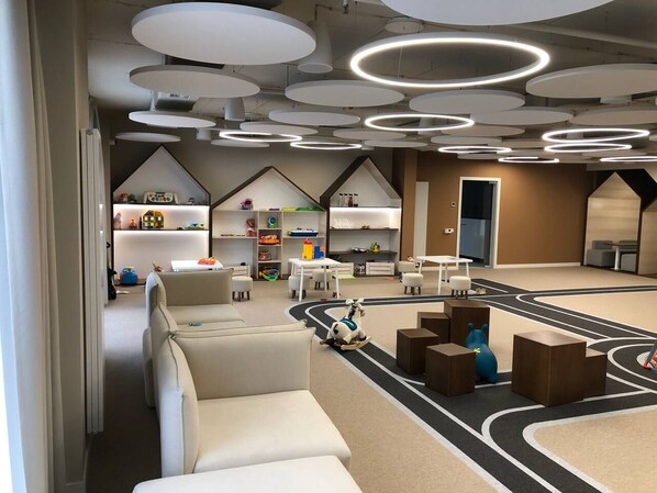 A modern children's play area with a racetrack, seating, and a toy car.