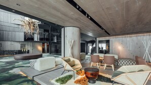 Un lobby espacioso con muebles modernos, una chimenea central y un techo alto con diseño único.