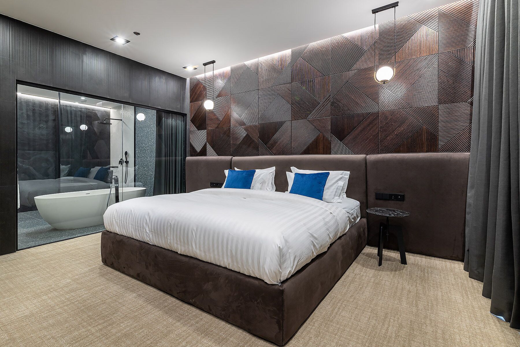 Quarto moderno com uma cama grande, cabine de chuveiro em vidro e parede com padrão geométrico.