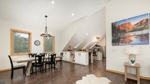 A modern kitchen with a dining area, wooden flooring, and a large window.
