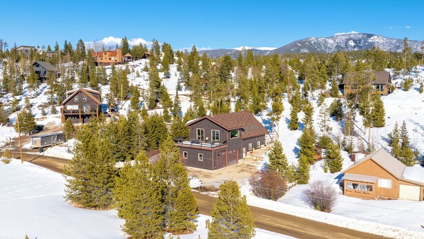 A residential area with houses surrounded by snow-covered trees and a mountain in the background.
