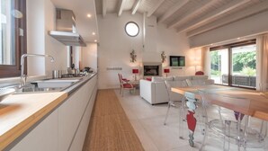 Une cuisine moderne dotée d’un îlot central, un coin repas avec une table en verre et un salon avec un canapé et un téléviseur.