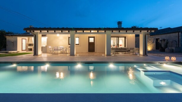 Une maison moderne dotée d’une piscine, d’un espace salon extérieur et d’un patio couvert.