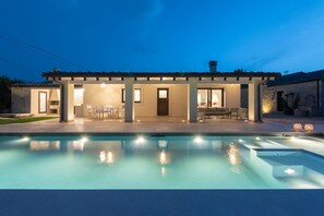 Ein modernes Haus mit Swimmingpool, Sitzgelegenheiten im Freien und einer überdachten Terrasse.