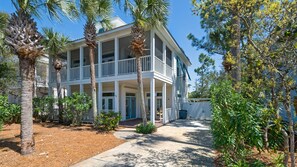 A two-story building with a balcony on the second floor, surrounded by palm trees and other greenery. - 3 Mins to Beach, Community Pool, Classic Home + Free Attraction Tickets! (Santa Rosa Beach)