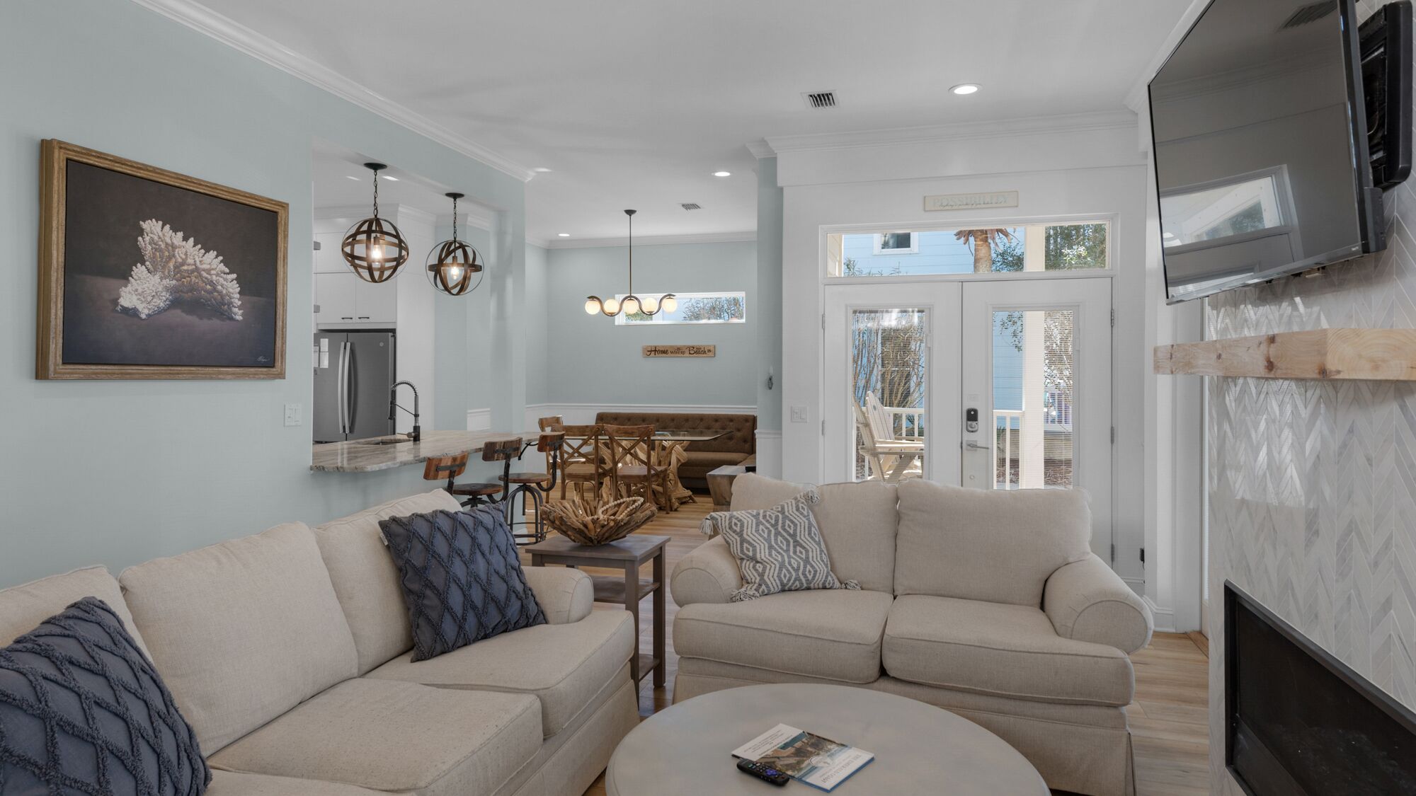 A modern living room with a sectional sofa, a dining area with a bench, and a kitchen in the background.