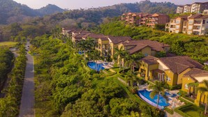 Een resort met meerdere gebouwen, een zwembad en weelderige begroeiing.