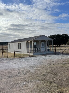 A single-story building with a porch and a fenced yard. - Cozy Cabin (Tuscola)