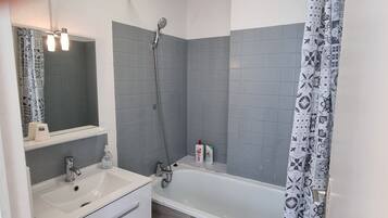 Ein Badezimmer mit einem weißen Waschbecken, einem Spiegel, einer Dusche mit Regendusche und einer Badewanne.