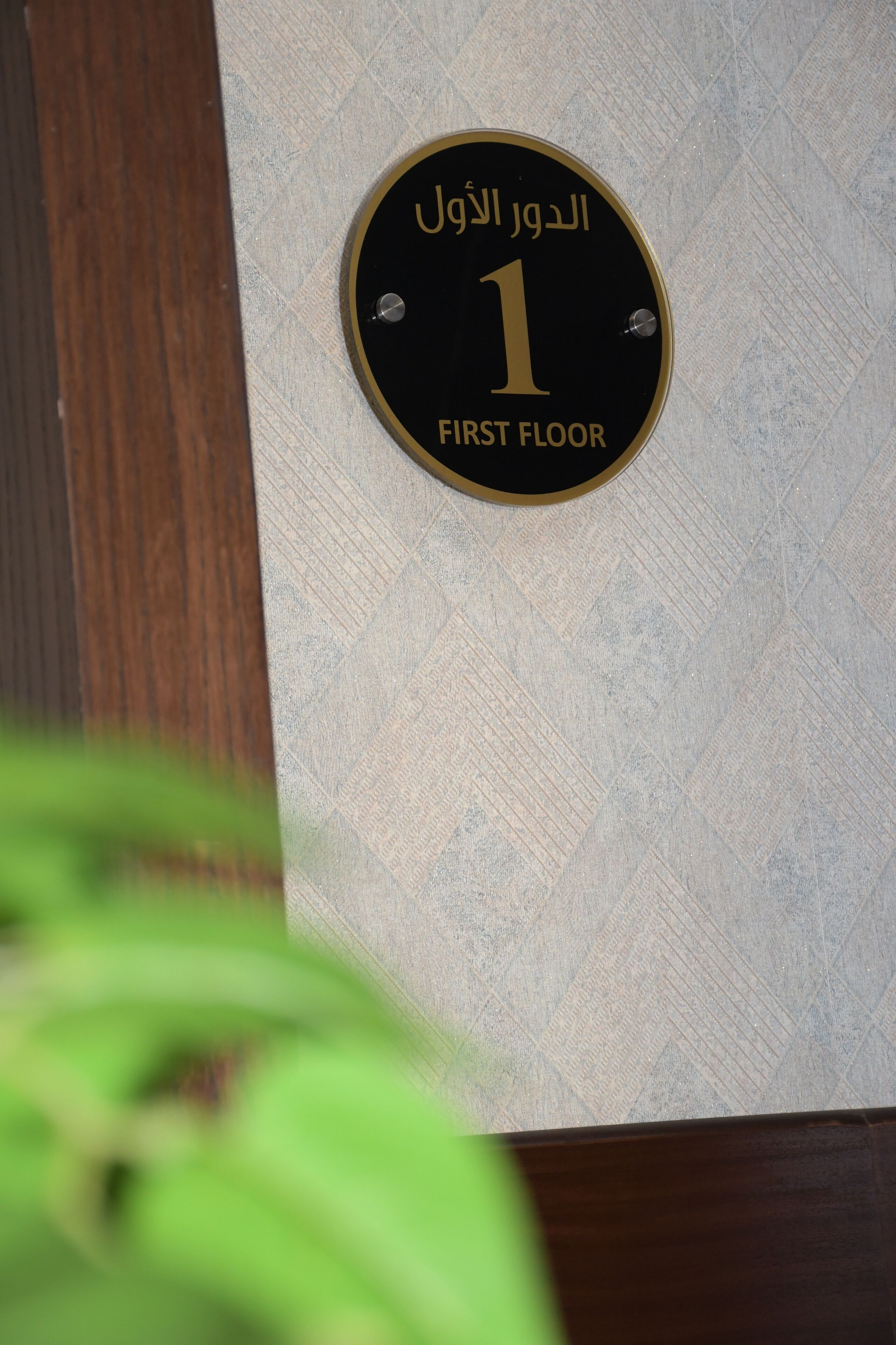 A sign indicating the first floor of a building with Arabic text.