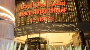 The exterior of the Shor Plaza Airport Hotel with a neon sign displaying the name and contact number. - Areen Hotel Airport (Jeddah)