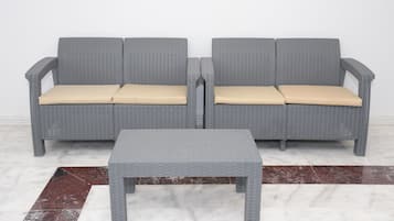 Ein graues Wicker-Sofa mit beigen Kissen und ein passender grauer Couchtisch auf einem Marmorboden.