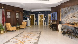 A lobby with a marble floor, a reception desk, and a large painting on the wall. - Areen Hotel Airport (Jeddah)
