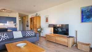 Een moderne woonkamer met een bank, salontafel, televisie en een houten kast.