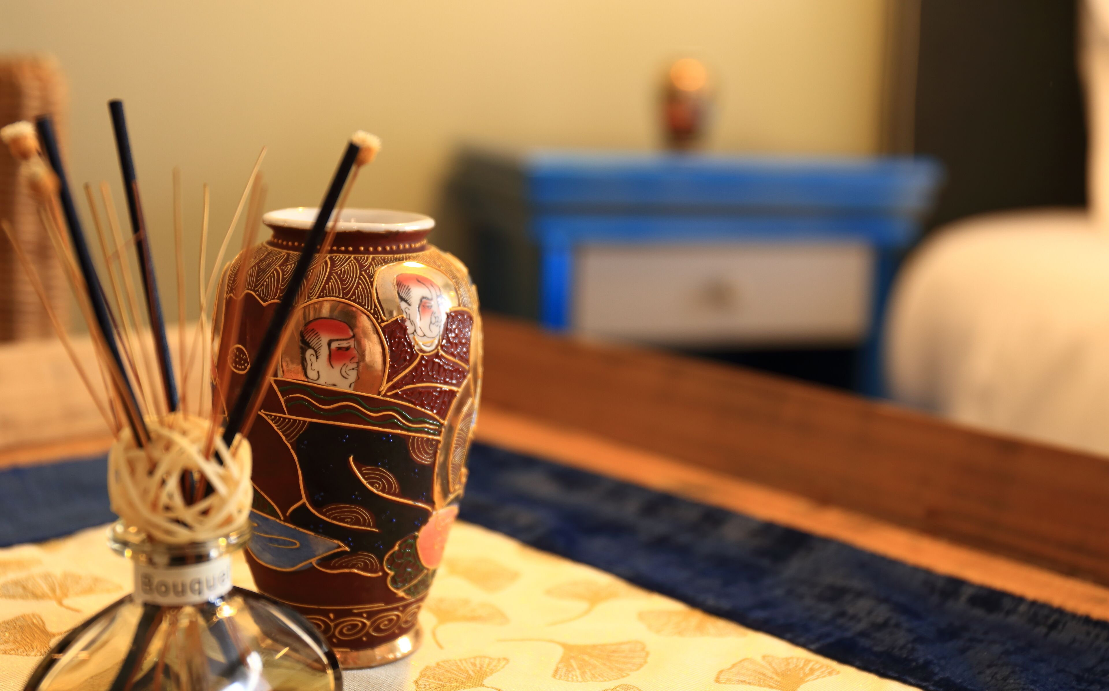 A decorative vase with intricate designs and a bottle of perfume on a table.