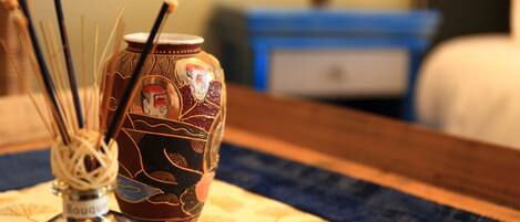 A decorative vase with intricate designs and a bottle of perfume on a table.